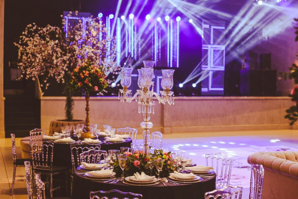 Elegant interior of a luxurious empty banquet hall with vibrant stage lighting and exquisite table settings.